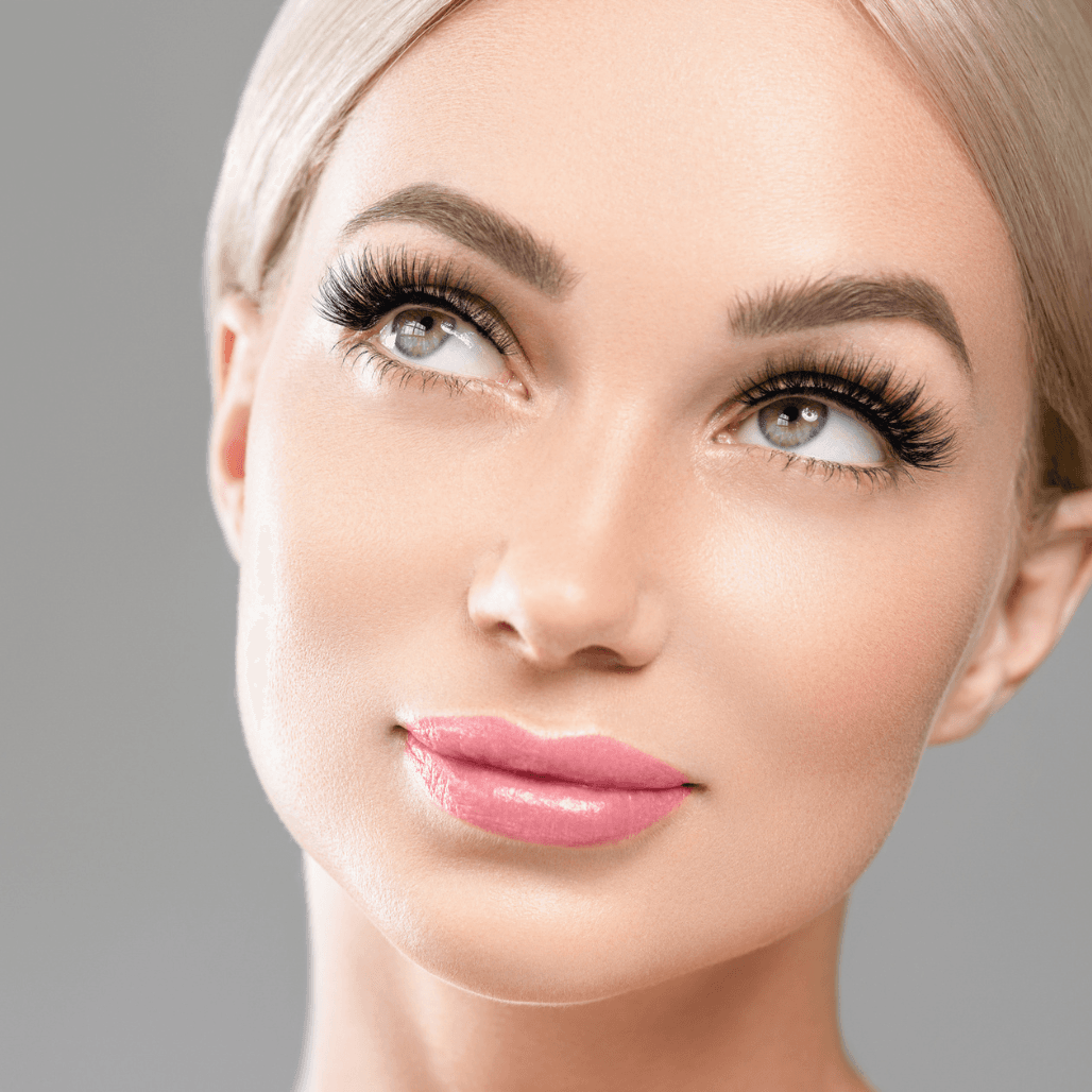 A close-up of a woman with flawless makeup, perfectly shaped brows, and long, voluminous lashes. Her soft expression and radiant skin highlight the results of professional lash and brow treatments available at Honeys Hair & Beauty in Taunton.